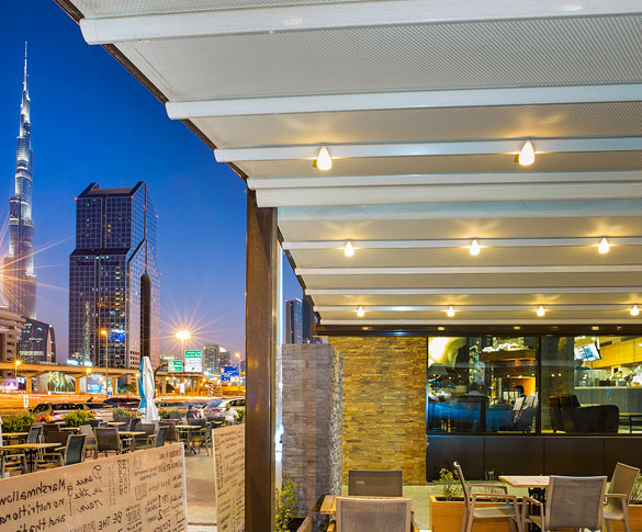Outdoor cafe shaded by a pergola with Burj Khalifa view at night