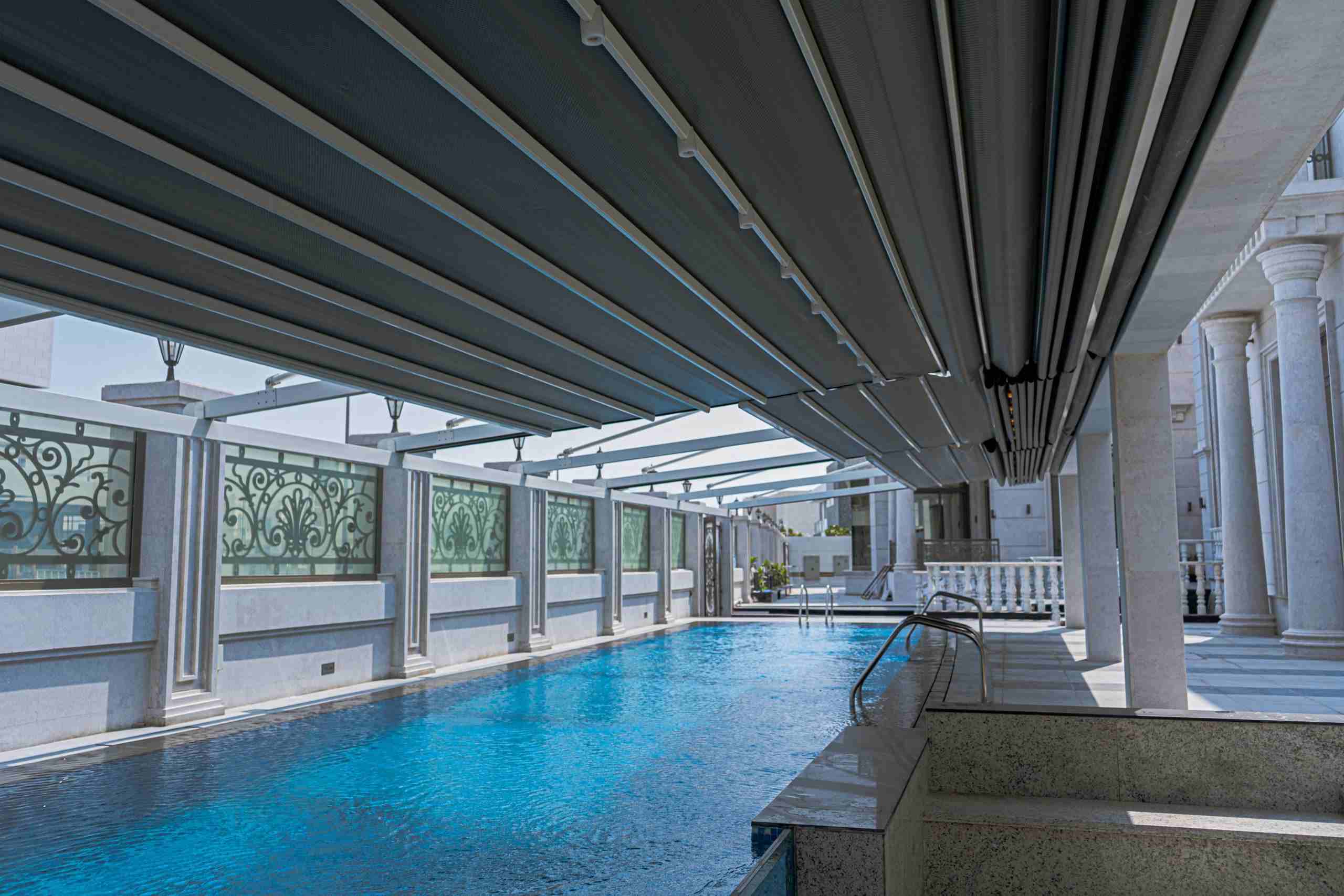 Pergola shading a swimming pool with partially open roof